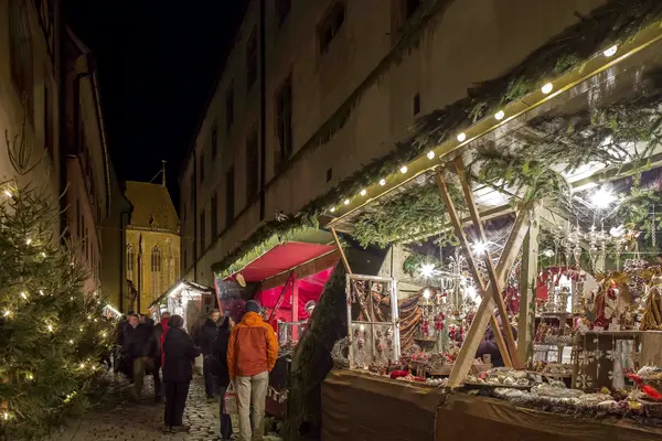 In an alley there are several stalls offering Christmas decorations and pastries.