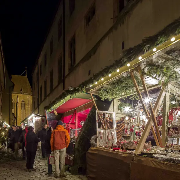 In an alley there are several stalls offering Christmas decorations and pastries.